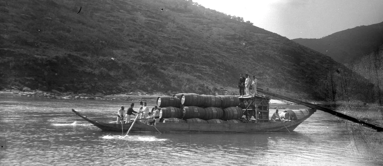 Barco rabelo carregado de pipas no Douro, com a espadela levantada — fotografia de época, Wikimedia Commons, domínio público