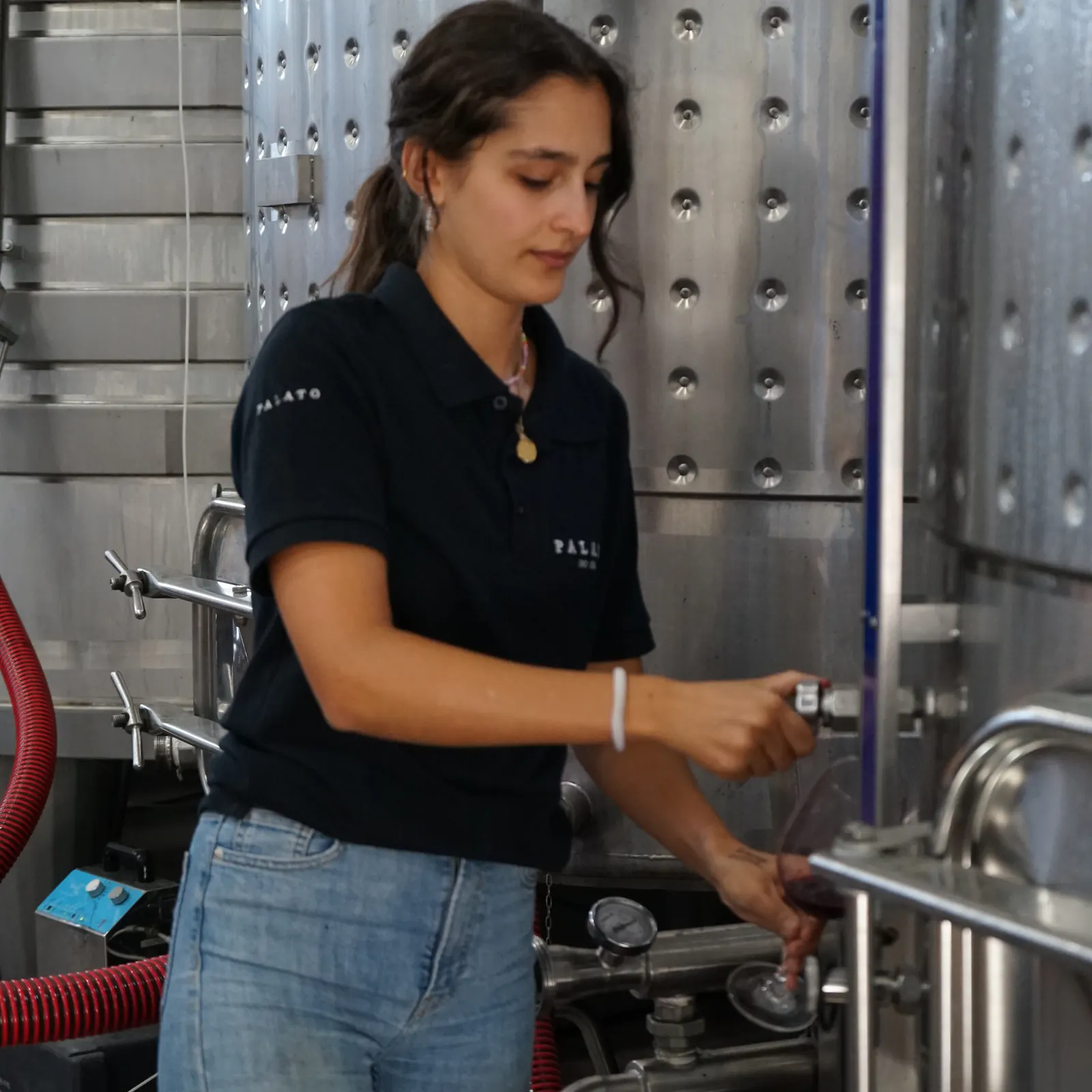 A team member draws wine from the tank into a glass in the winery